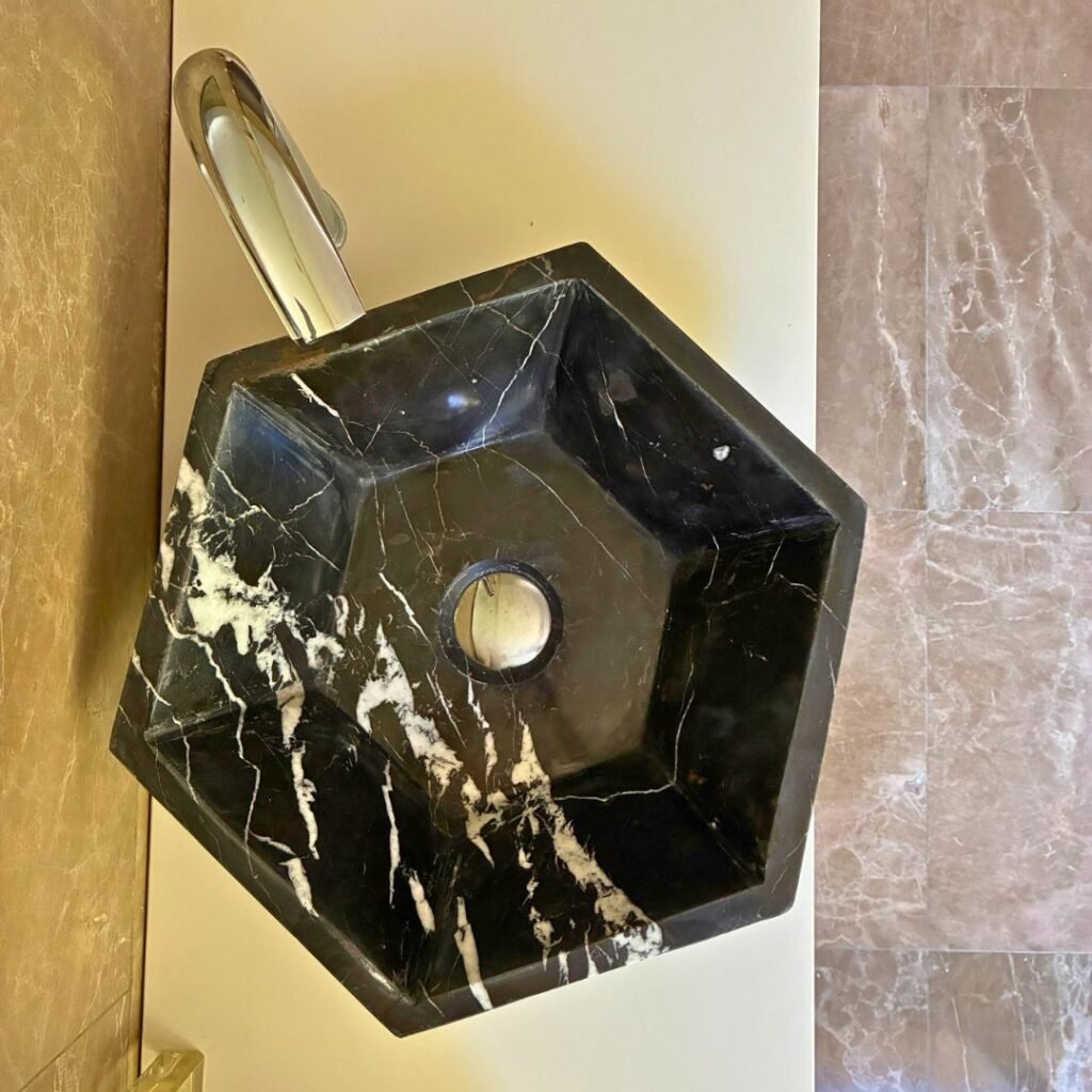 Lavabo de mármol negro moderno con diseño hexagonal sobre mueble de baño