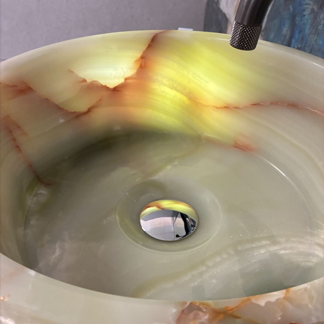Lavabo de piedra natural onix con acabado rugoso sobre encimera de granito