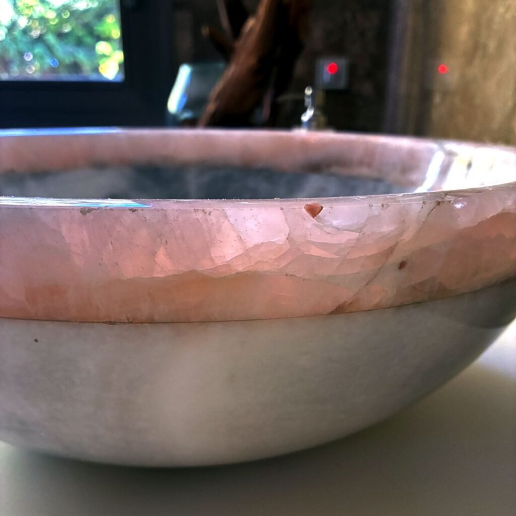 Lavabo redondo de mármol blanco con acabado artesanal y borde rosa