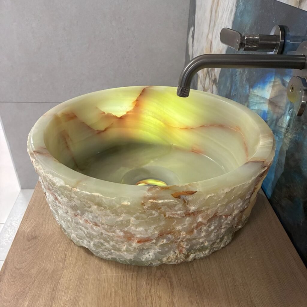 Lavabo de piedra natural onix con acabado rústico sobre encimera de baño