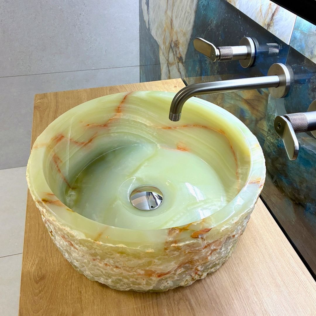 Lavabo de ónix natural con superficie irregular sobre mueble de baño