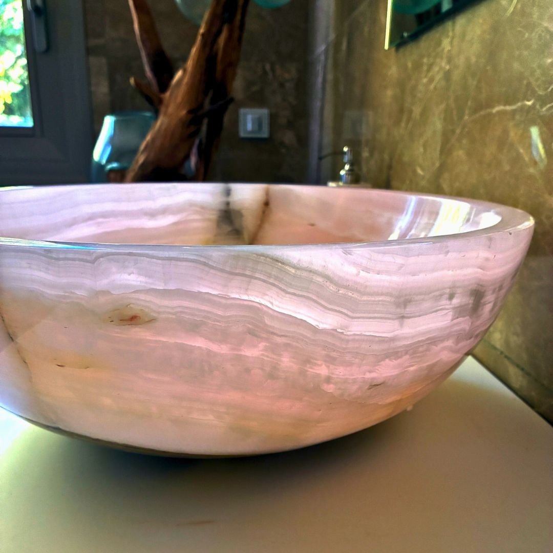 Lavabo de ónix rosa moderno en forma de cuenco sobre encimera