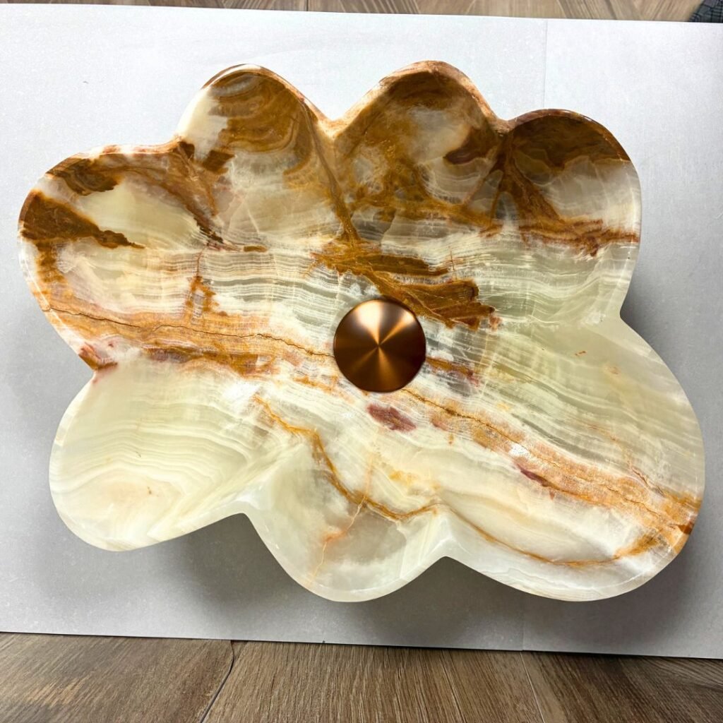 Lavabo de diseño moderno en piedra natural con forma de concha irregular sobre encimera de baño