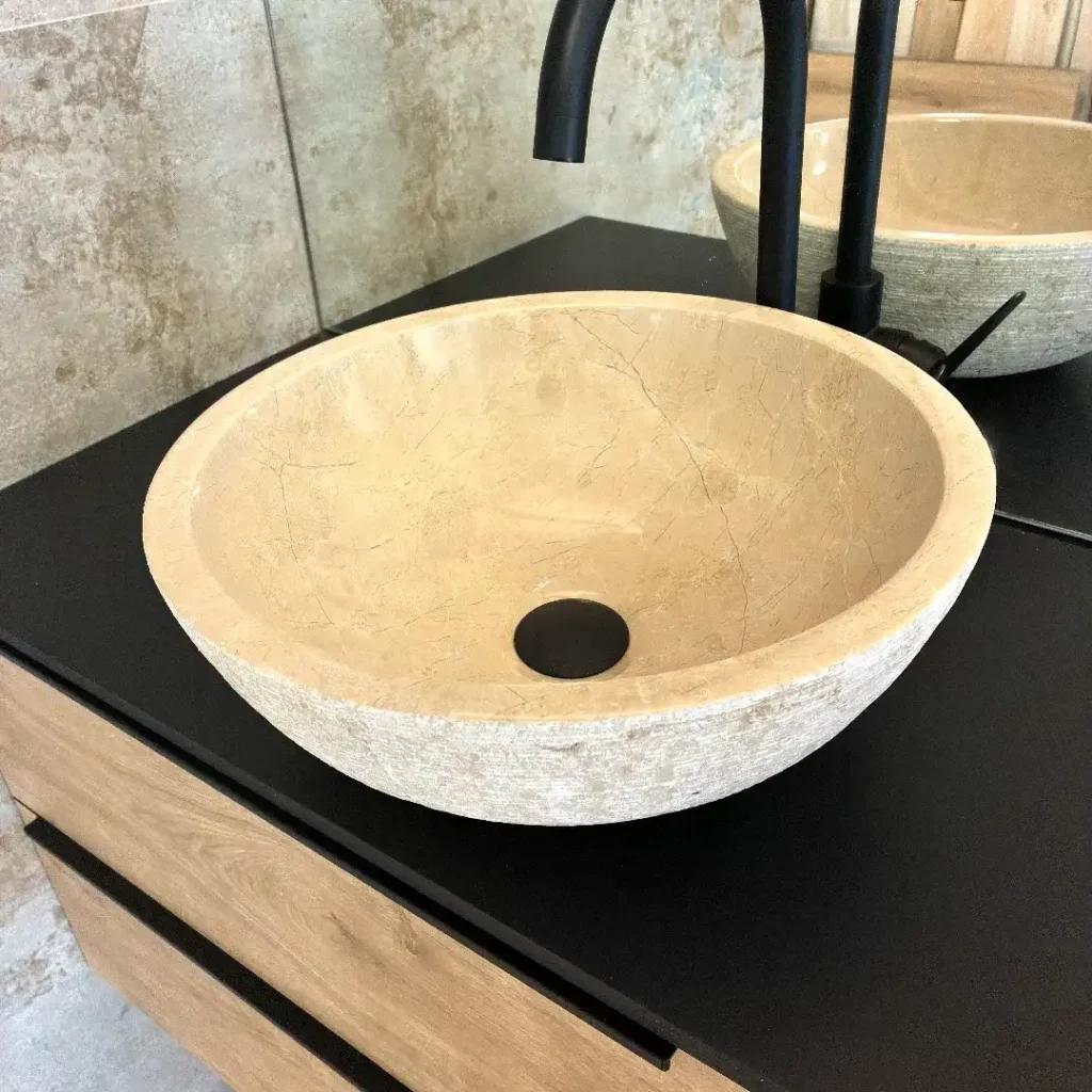 Lavabo de mármol crema redondo con acabado pulido y grifo negro