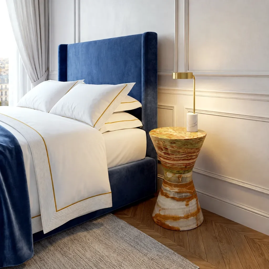Mesita de noche de ónix verde y blanco junto a la cama en un dormitorio moderno, usada como mesa auxiliar.