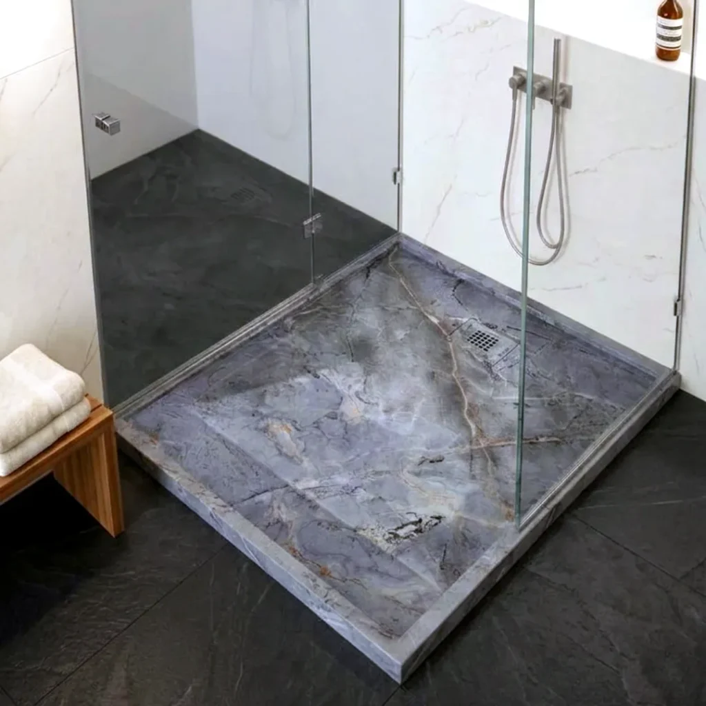 Plato de ducha mármol gris instalado en un baño contemporáneo, con perfil extraplano y acabado de carga mineral que se integra con elegancia en el pavimento.